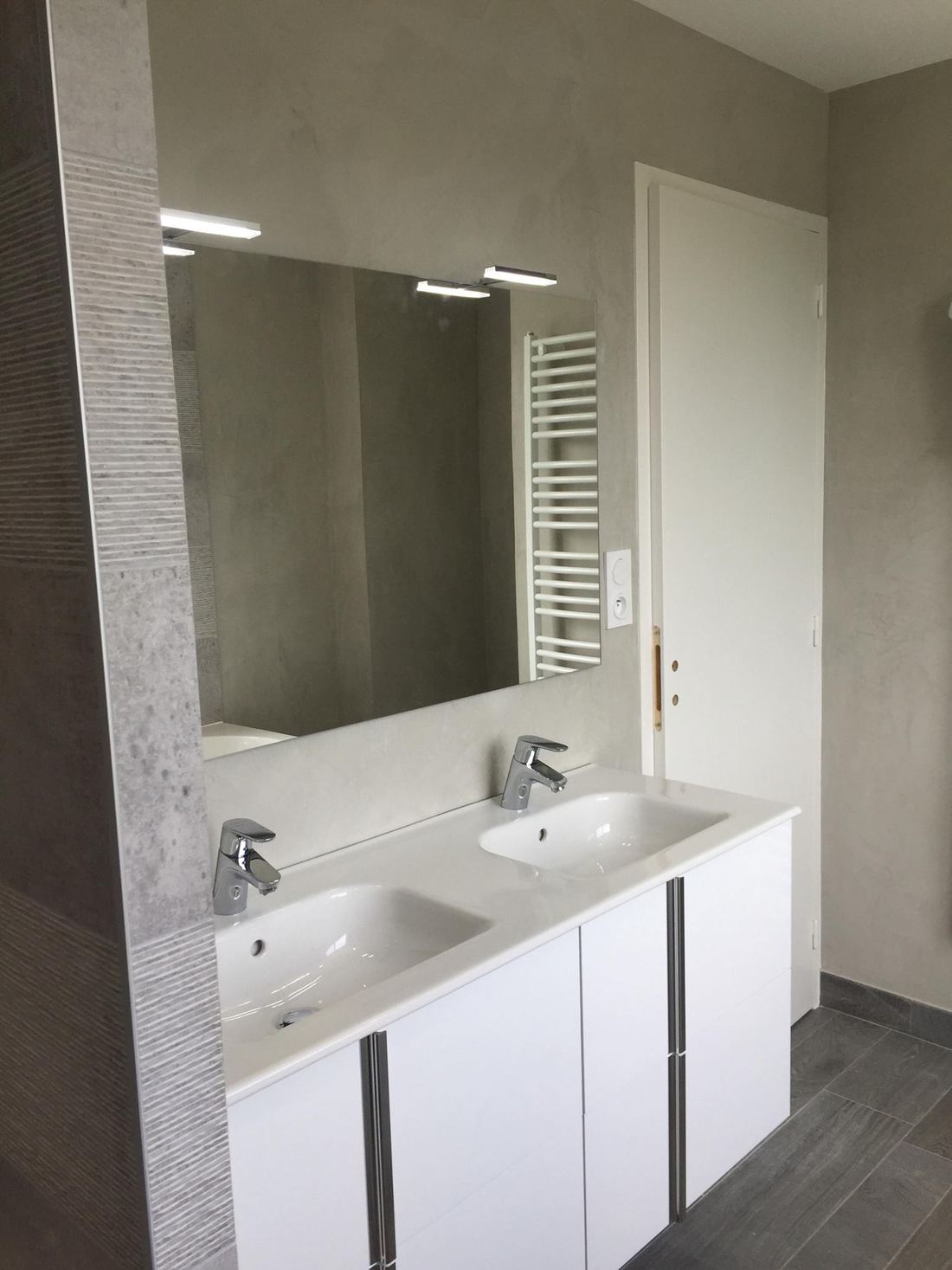 Salle de bains rénovée avec double vasque blanche et grand miroir