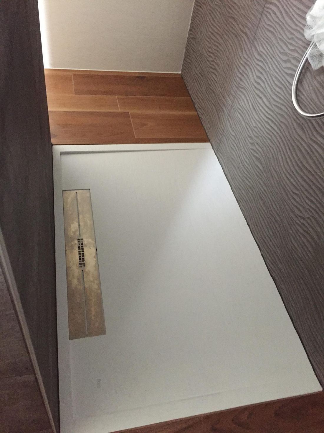 Receveur de douche extra-plat au pied d'une faïence en relief et d'un sol effet bois