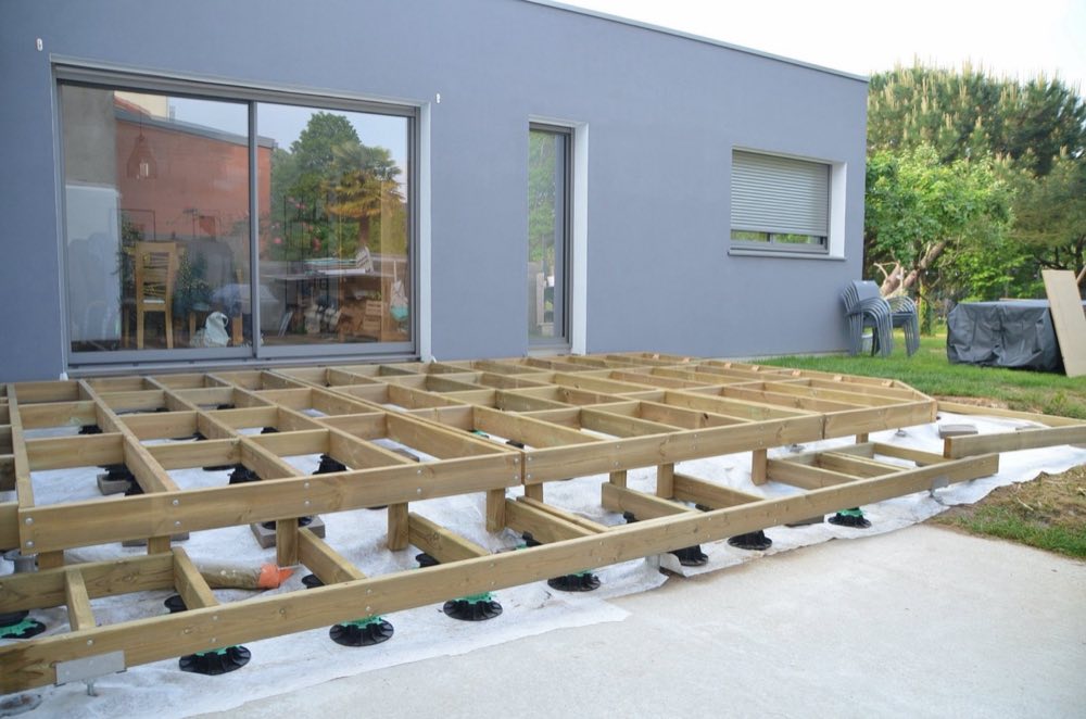 Structure bois d'une terrasse en cours de pose devant une maison