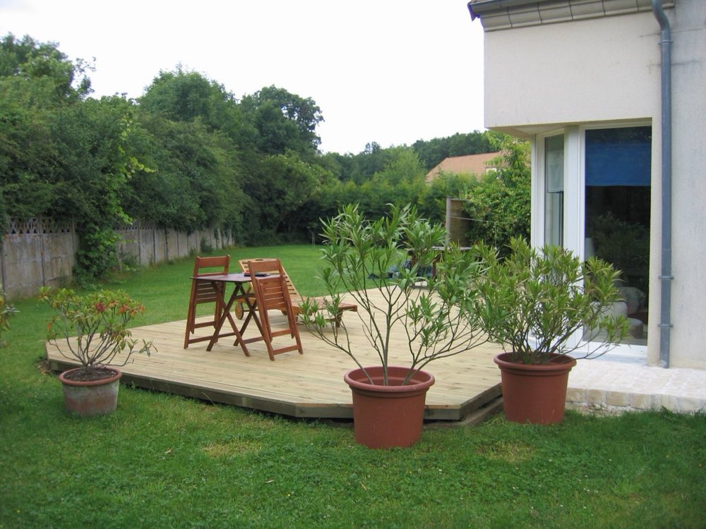 Terrasse en pin posée au fond d'un jardin